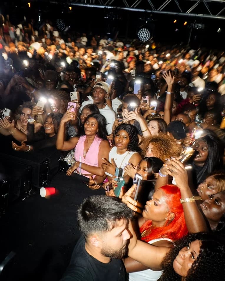 A concert crowd with phone lights raised toward the stage