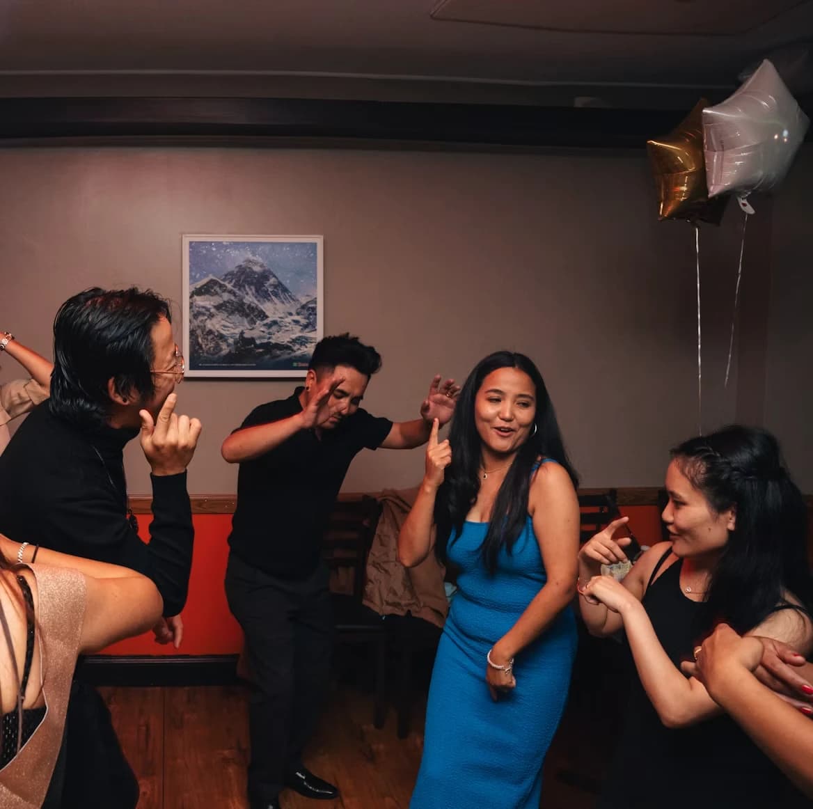 A small room of people dancing at a private party